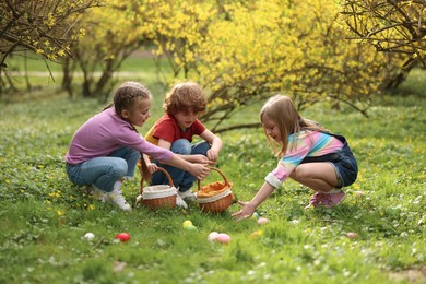 Easter celebration. Cute little children hunting eggs outdoors