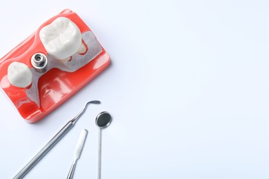 Photo of Educational model of gum with post for dental implant between teeth and medical tools on white background, top view