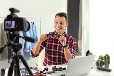 Photo of Fashion blogger with glasses recording video on camera at home