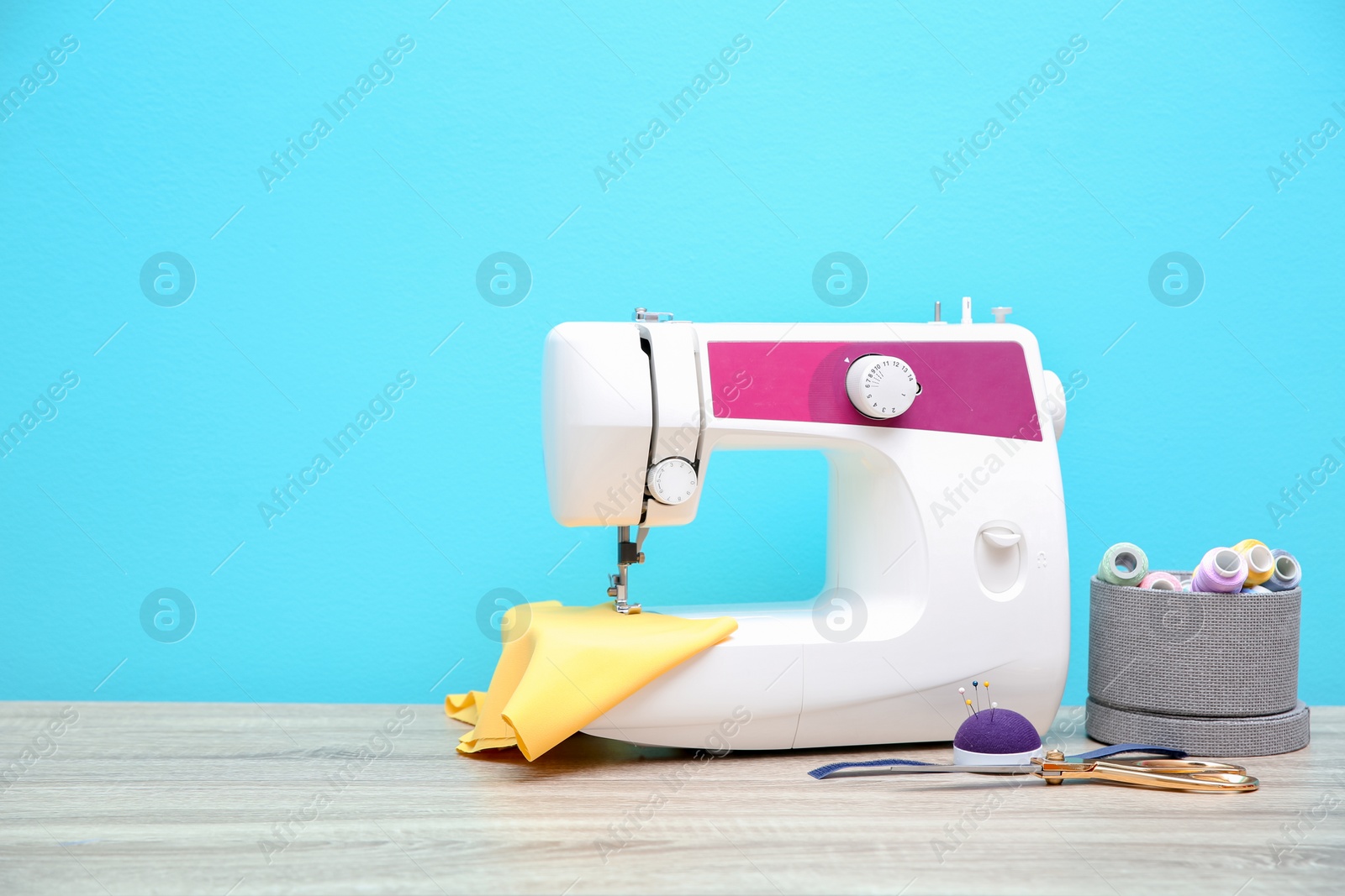 Photo of Sewing machine on table against color background