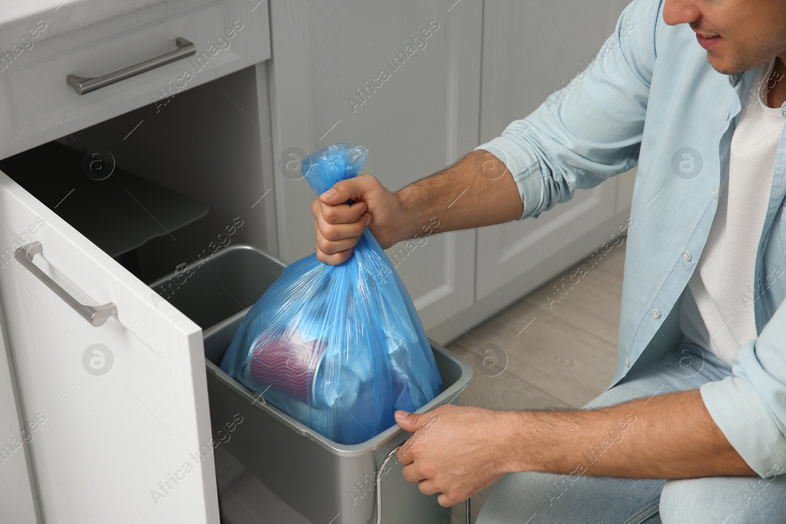 Photo of Man taking garbage bag out of bin at home, closeup