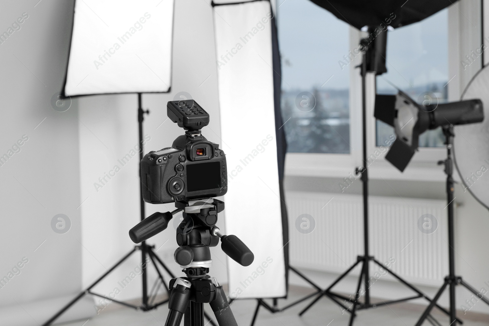 Photo of Camera on tripod and professional lighting equipment in modern photo studio, space for text