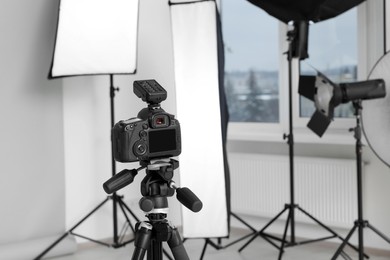 Photo of Camera on tripod and professional lighting equipment in modern photo studio, space for text
