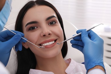 Photo of Dentist examining young woman's teeth in modern clinic
