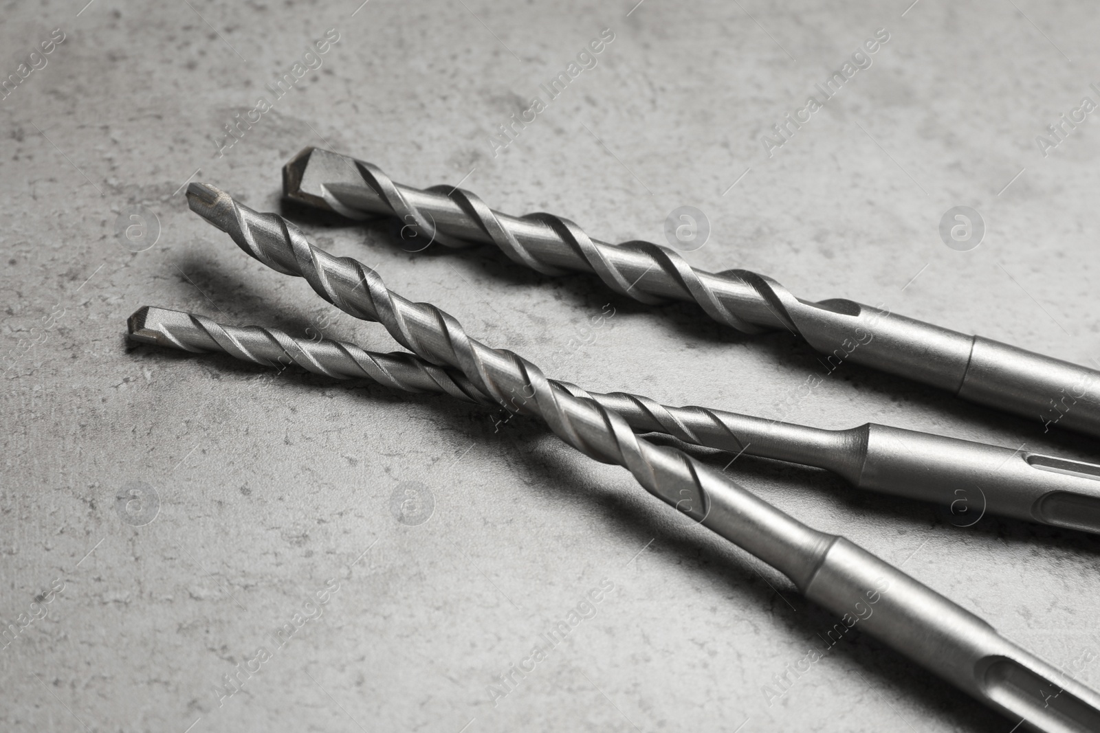 Photo of Different drill bits on grey table, closeup