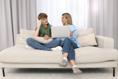 Photo of Happy teenage son and his mother with laptop at home