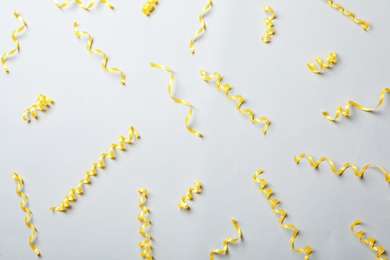 Yellow serpentine streamers on light background, flat lay