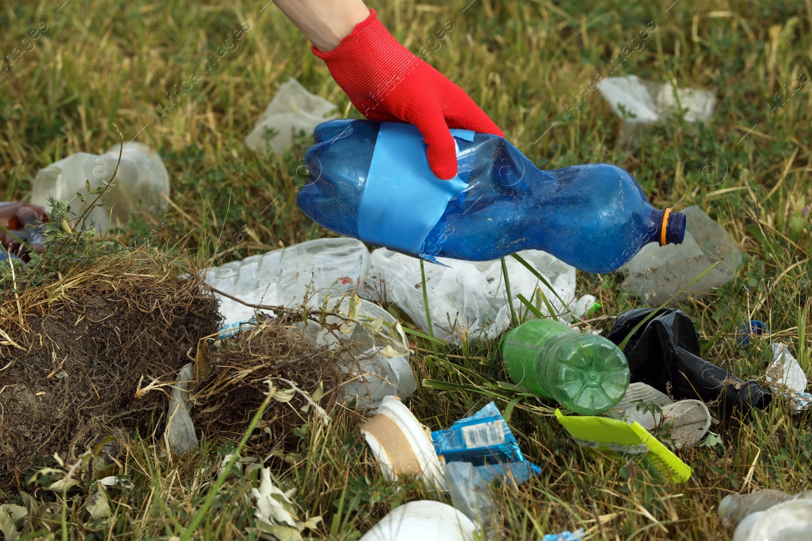 Photo of Woman in gloves collecting garbage in nature, closeup