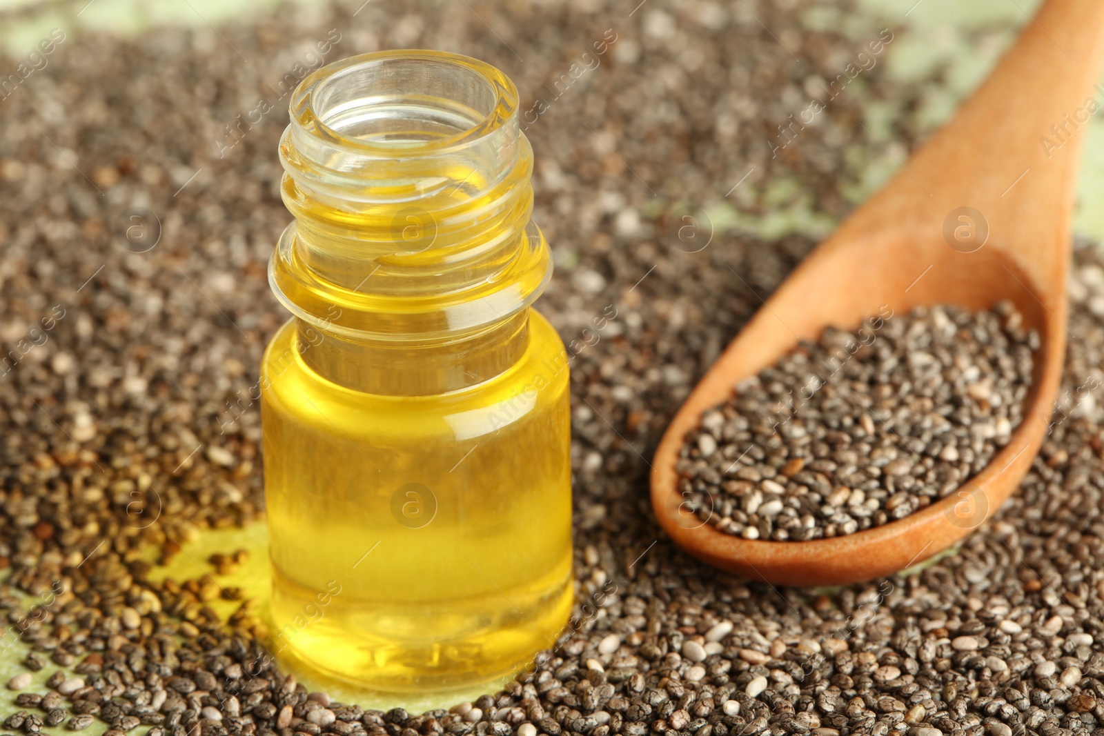 Photo of Bottle of oil, spoon and chia seeds on table, closeup. Space for text