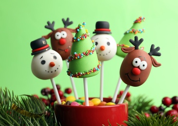 Photo of Delicious Christmas themed cake pops on green background, closeup