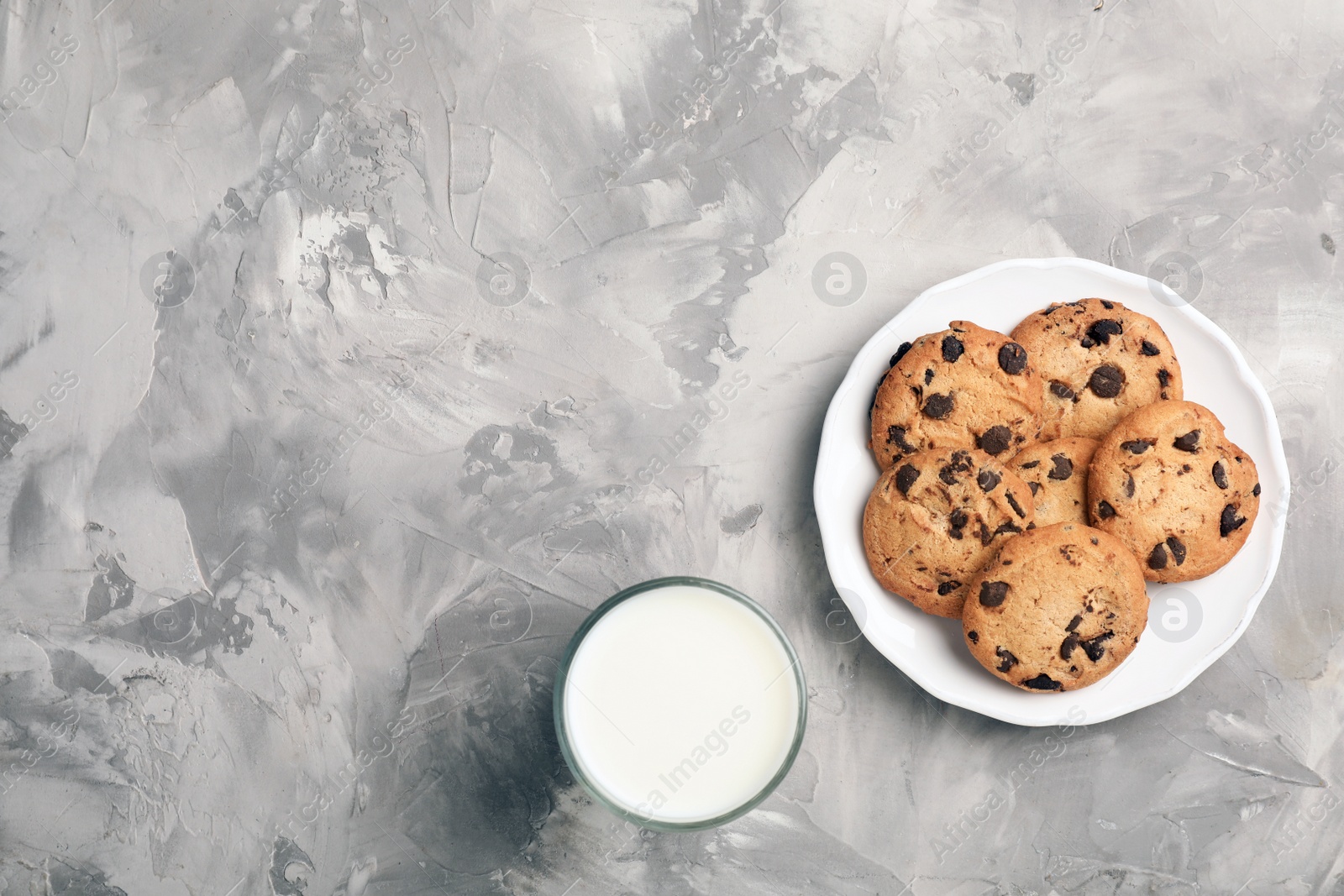 Photo of Flat lay composition with chocolate cookies and glass of milk on gray background. Space for text