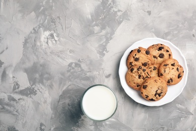 Flat lay composition with chocolate cookies and glass of milk on gray background. Space for text