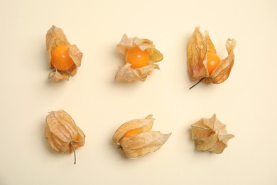 Ripe physalis fruits with dry husk on beige background, flat lay