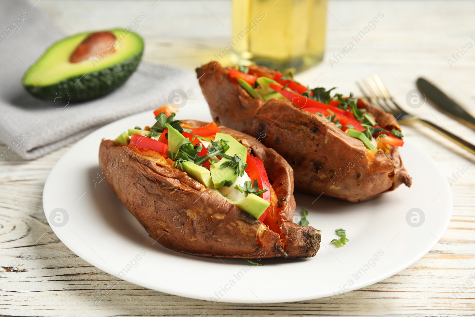 Photo of Plate with stuffed sweet potatoes on white wooden table, closeup