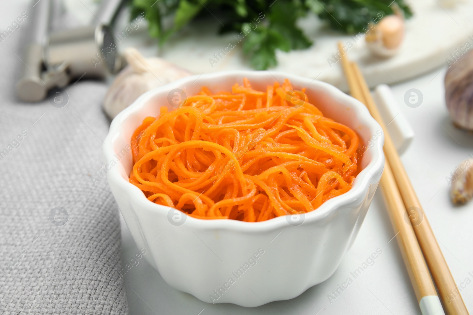 Photo of Delicious Korean carrot salad in bowl on white table