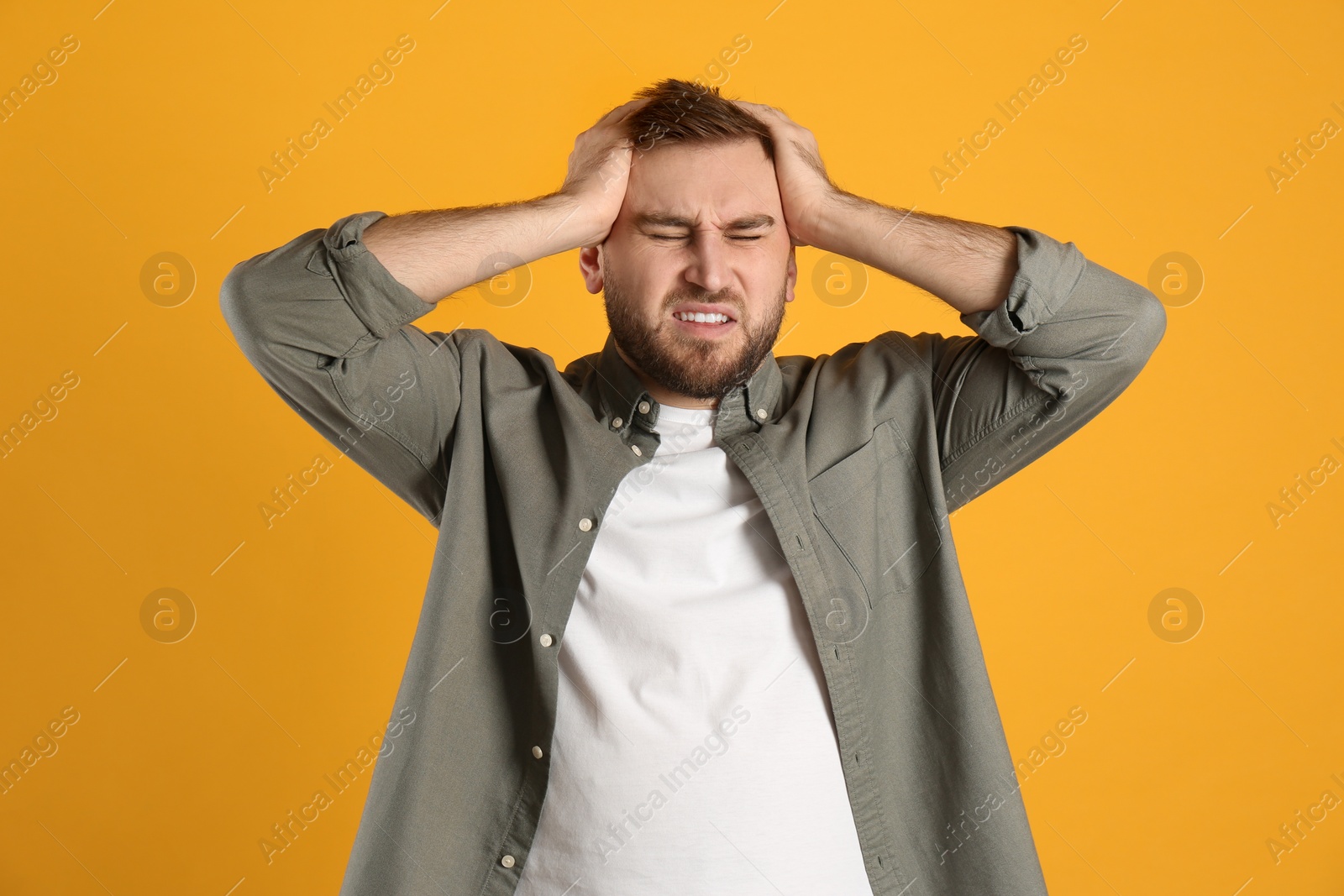 Photo of Man suffering from migraine on yellow background