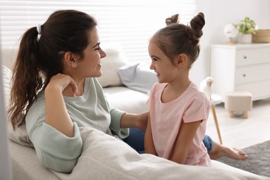 Photo of Young mother and her daughter spending time together on sofa at home