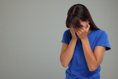 Photo of Resentful woman covering face with hands on light grey background, space for text