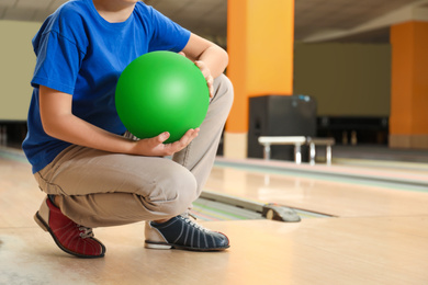 Photo of Little boy with ball in bowling club, closeup