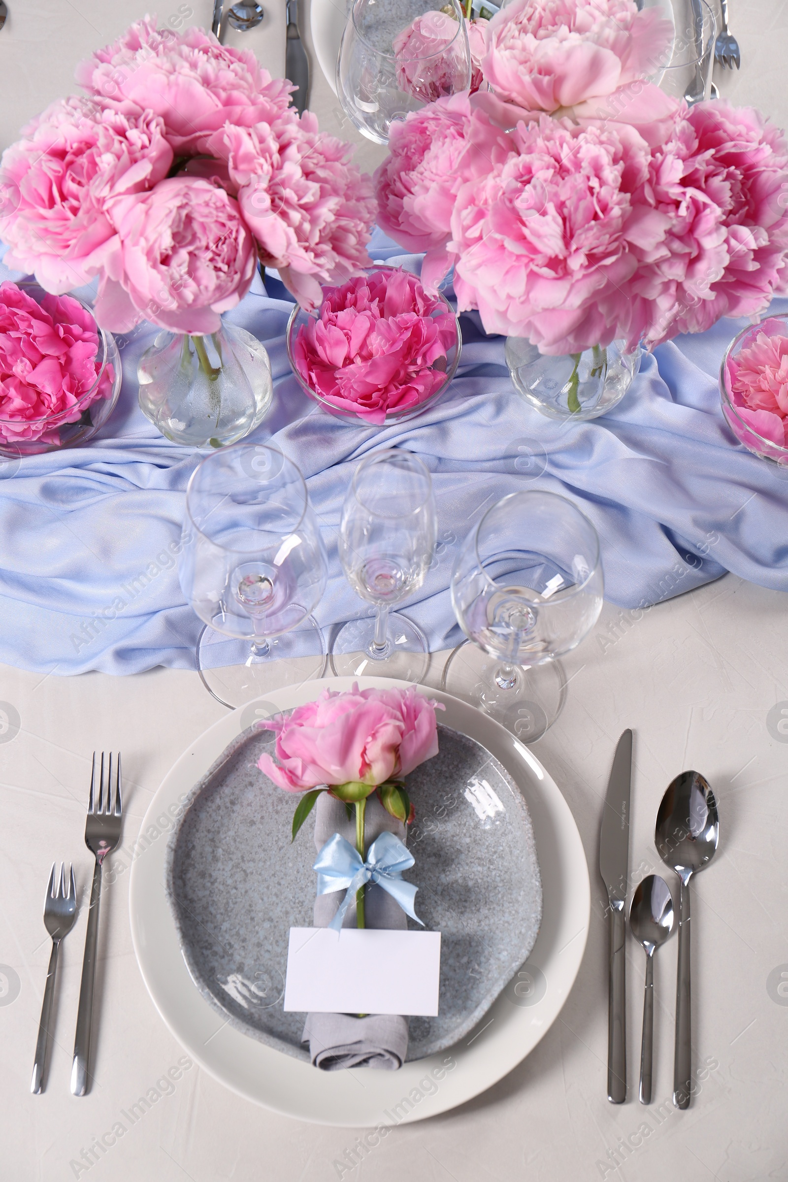 Photo of Stylish table setting with beautiful peonies, napkin and blank card, above view