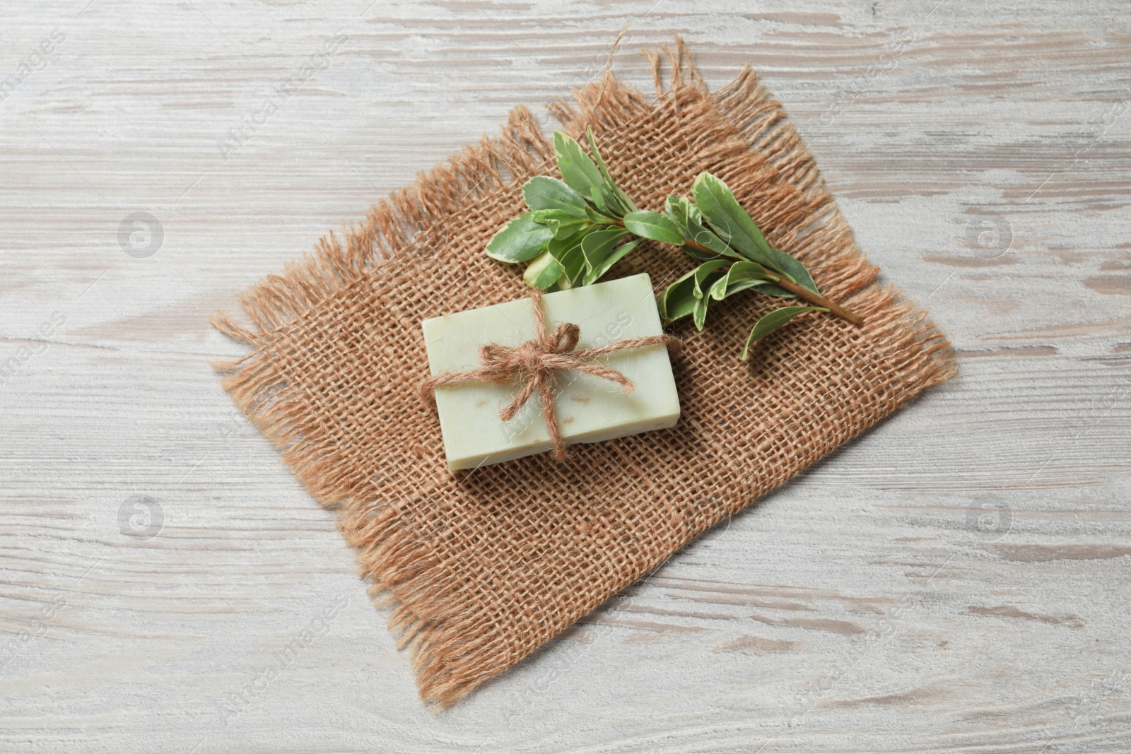 Photo of Soap bar and green plant on wooden table, top view