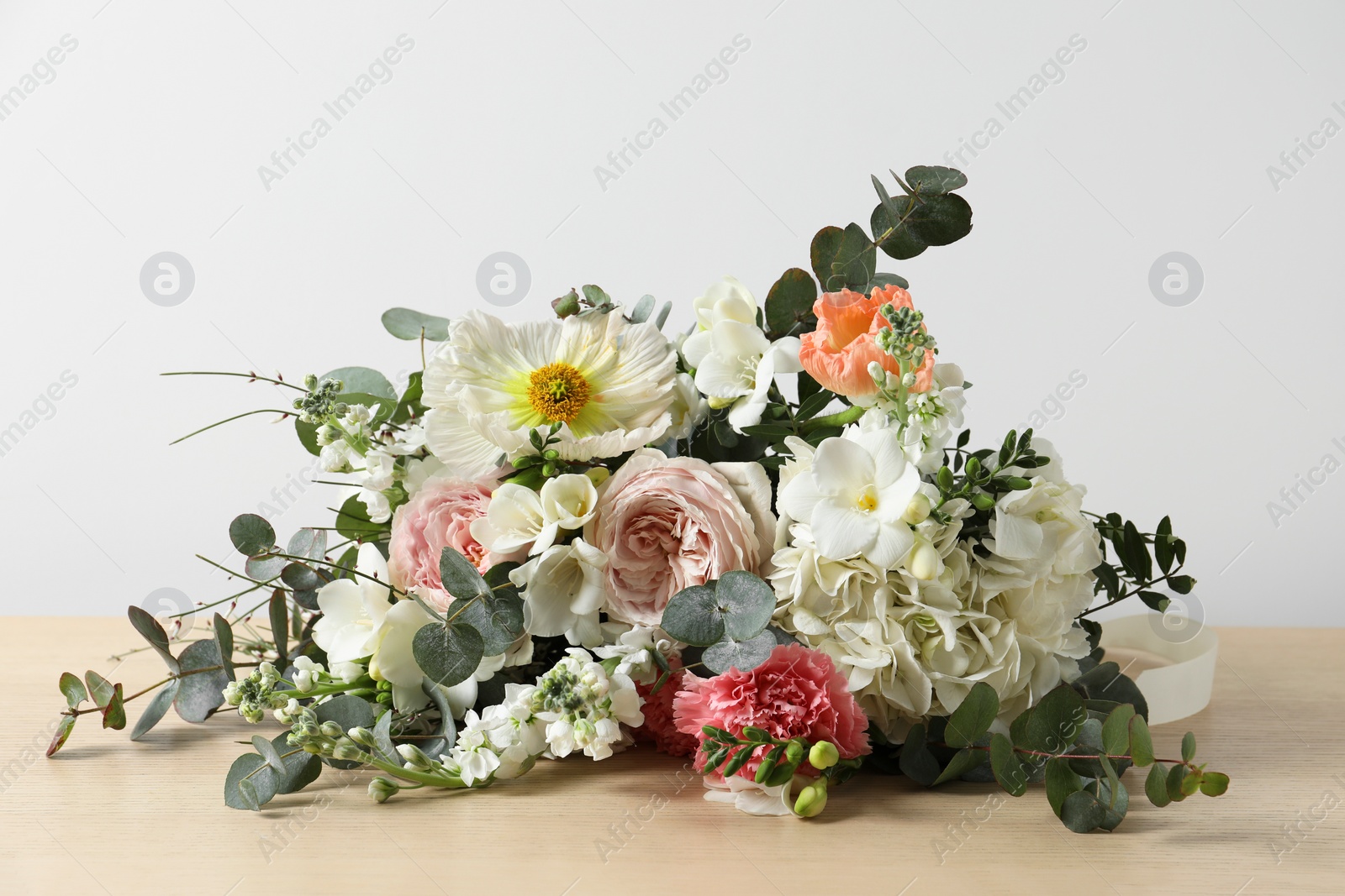 Photo of Bouquet of beautiful flowers on wooden table against white wall