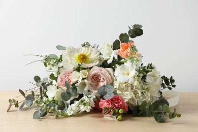 Photo of Bouquet of beautiful flowers on wooden table against white wall