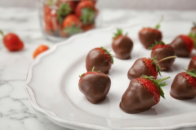 Plate with chocolate covered strawberries on table, closeup