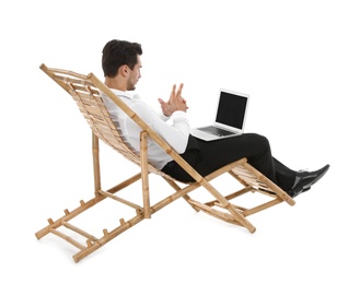 Photo of Young businessman with laptop on sun lounger against white background. Beach accessory