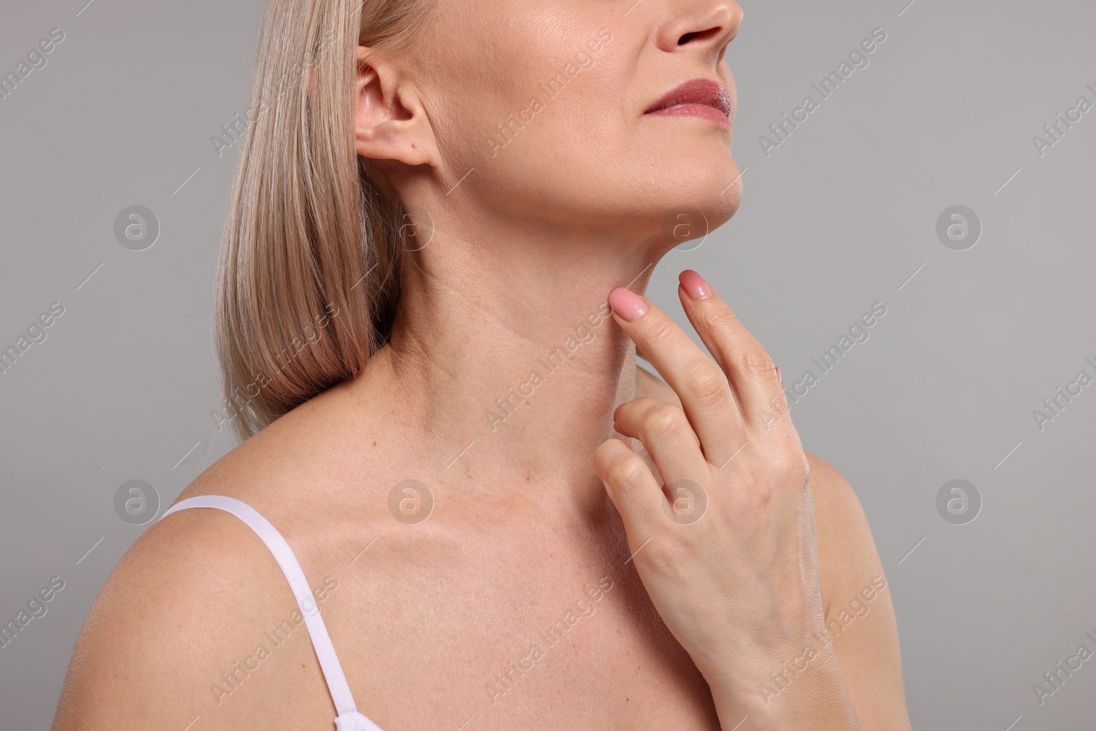 Photo of Woman touching her neck on grey background, closeup