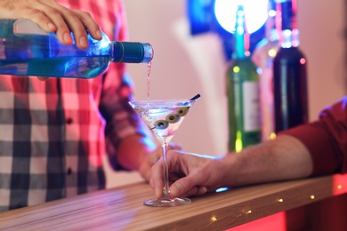 Photo of Barman pouring martini into glass at pub, closeup