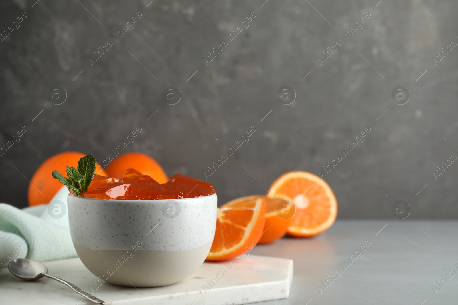 Photo of Composition with orange jelly in bowl on table against grey background. Space for text