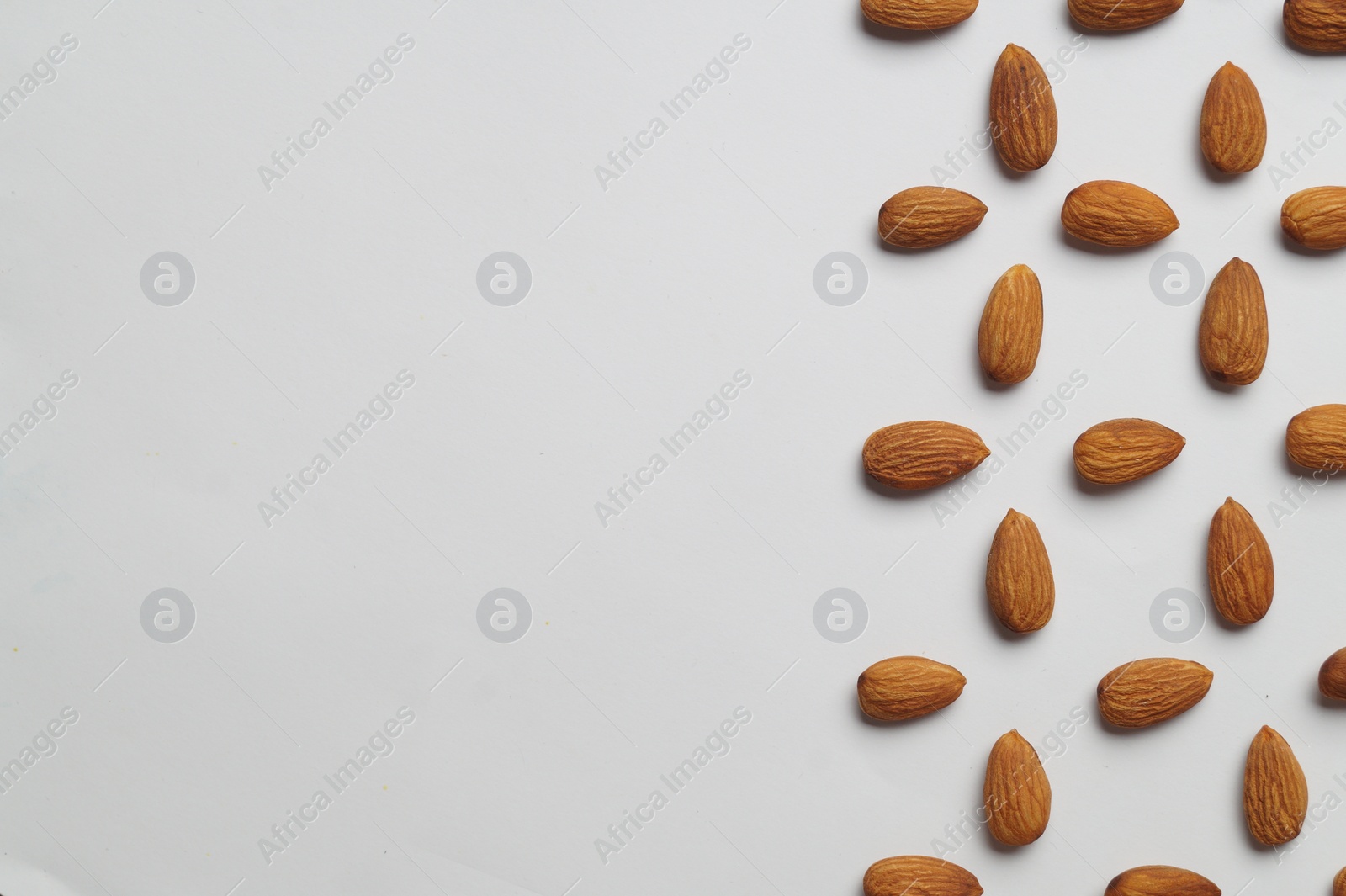 Photo of Delicious almonds on white background, flat lay. Space for text