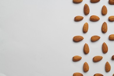 Delicious almonds on white background, flat lay. Space for text