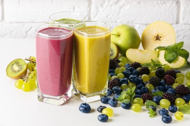 Photo of Fresh colorful fruit smoothies and ingredients on white table