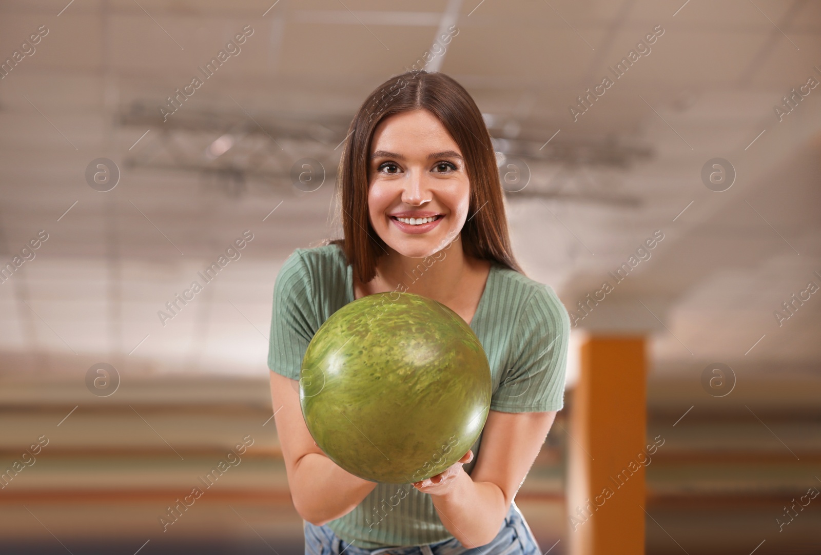 Photo of Young woman with ball in bowling club