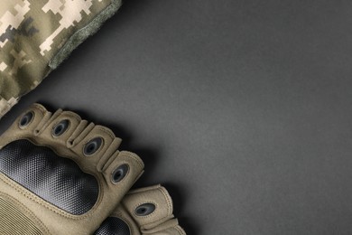 Photo of Tactical gloves and uniform on black background, flat lay with space for text. Military training equipment