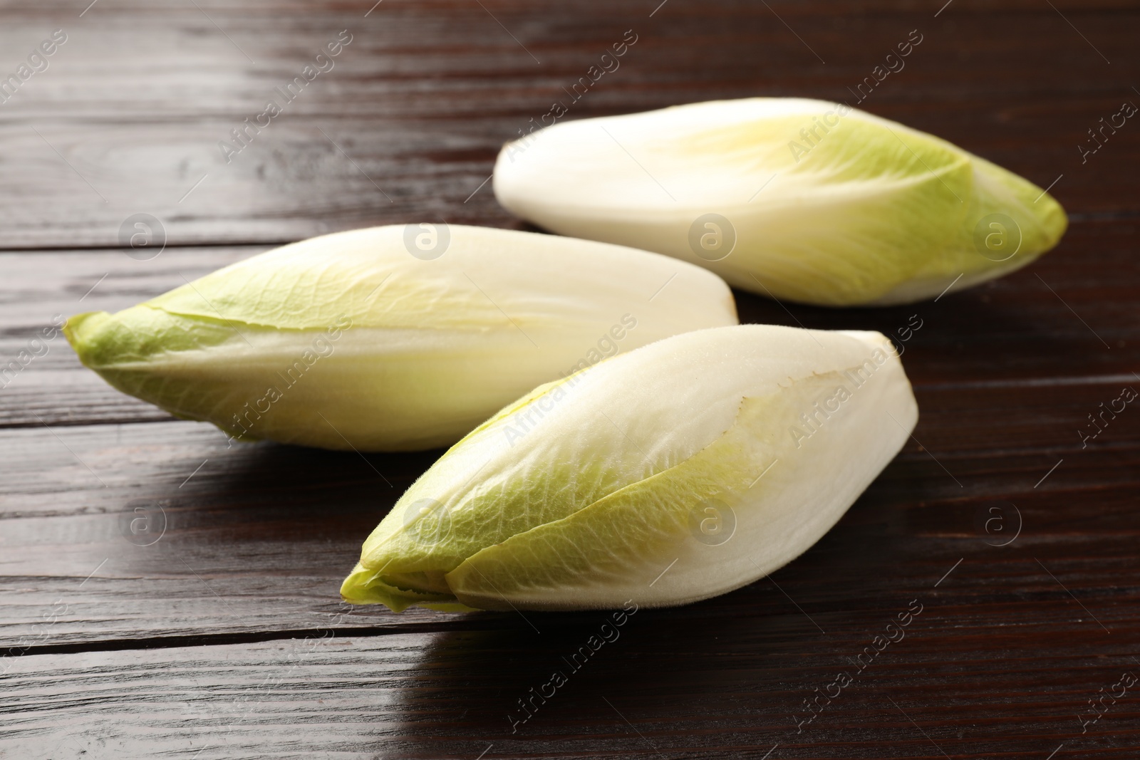 Photo of Raw ripe chicories on wooden table, closeup