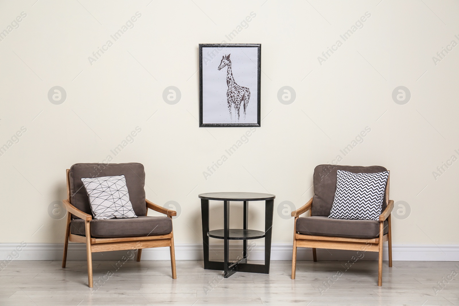 Photo of Room interior with modern armchairs and table near light wall