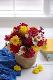 Photo of Beautiful bouquet and books on white wooden table near window