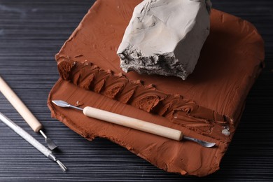 Photo of Clay and set of modeling tools on dark gray wooden table, above view