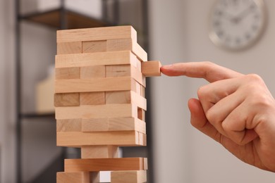 Playing Jenga. Man building tower with wooden blocks indoors, closeup