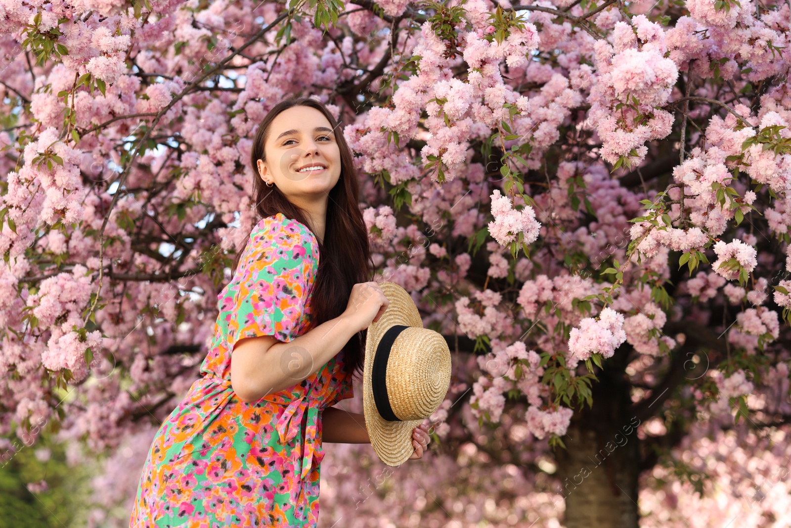 Photo of Beautiful woman with straw hat near blossoming tree on spring day