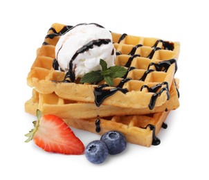 Tasty Belgian waffles with ice cream, berries and chocolate syrup on white background