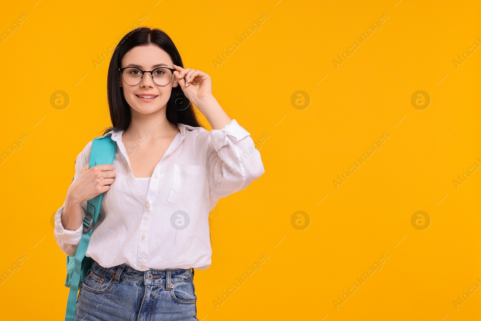 Photo of Smiling student in glasses on yellow background. Space for text