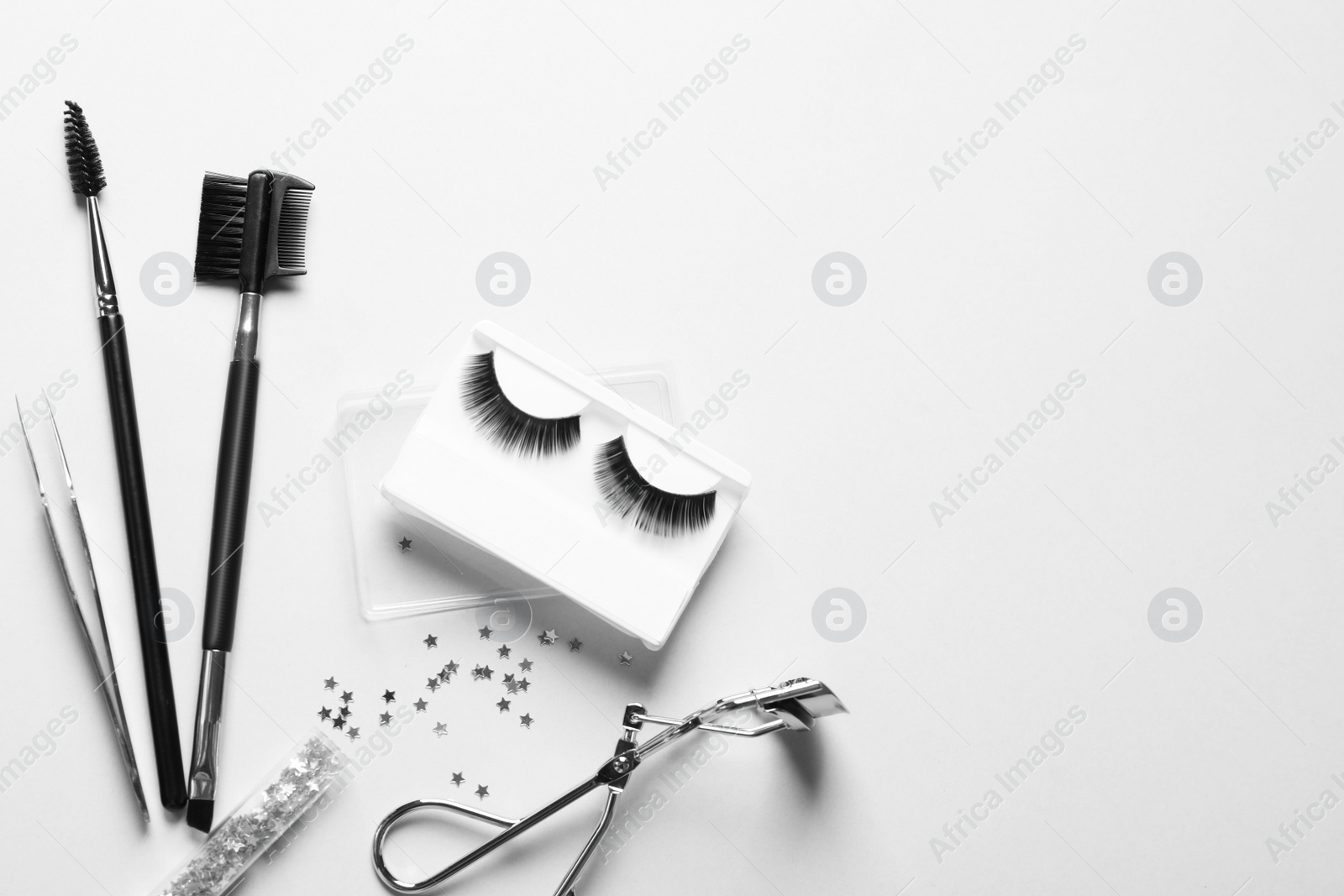 Photo of Composition with false eyelashes and tools on white background, top view