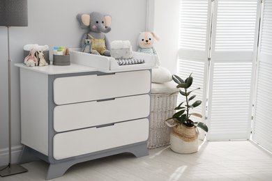 Changing tray and pad on chest of drawers in baby room. Interior design