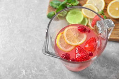 Photo of Jug of fresh lemonade with berries on table