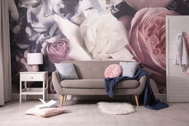 Photo of Modern sofa near wall with floral wallpaper. Stylish living room interior
