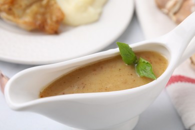 Photo of Delicious turkey gravy in sauce boat on table, closeup